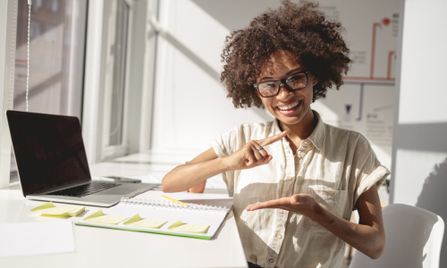 dark skin girl with glasses signing while sitting at a desk